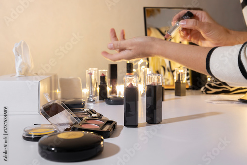 Woman applying soft pink lipstick on her wrist near the makeup counter at the beauty store. Compare colors and choosing right lipstick for her outfit