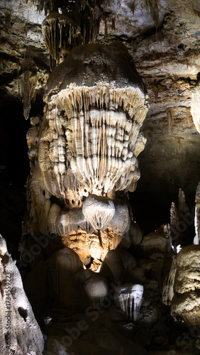 Detailed close-up view of a stalactite formation inside a natural limestone cave, showcasing mineral textures and geological beauty.
