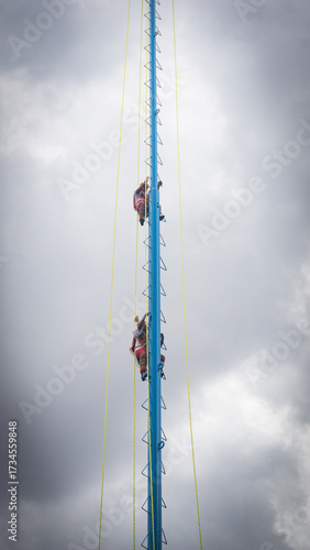 Indigenous performers climbing the tall pole used in the 
