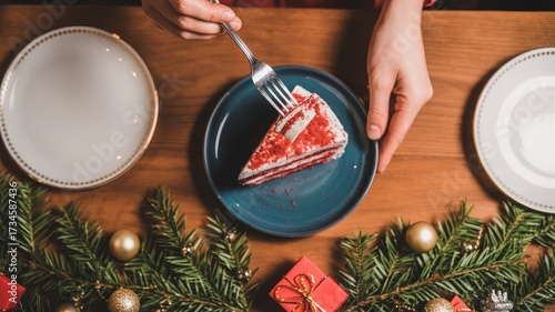 Red velvet cake lifted by fork on festive wood table with evergreen trim and warm holiday glow