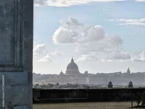View of St. Peter’s Basilica in Vatican City on a rainy day. Raindrops on the lens and dramatic clouds in the sky create a unique, moody atmosphere that contrasts with the iconic dome of the church.