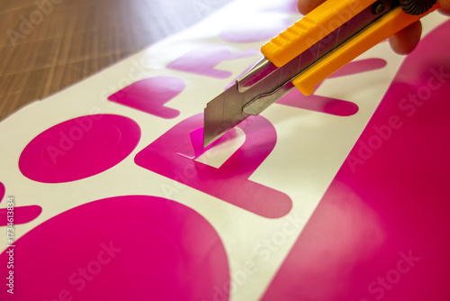 Plotter cutting of vinyl film in production.Clean the adhesive film with a stationery knife.Cut out the sticker to advertise the store.