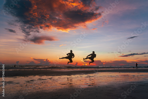 Two silhouetted figures doing jump sidekicks against the  backdrop of a Marco Island sunset.