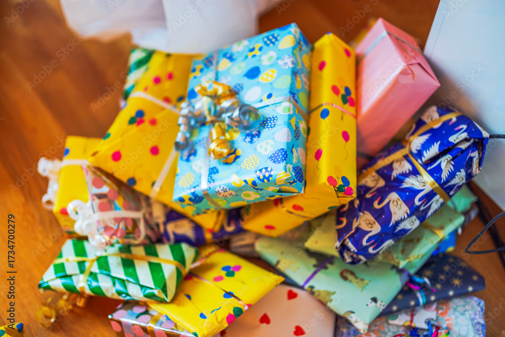 Obraz premium Close up view of children gifts wrapped in colorful paper with ribbons lying on wooden floor. Sweden.