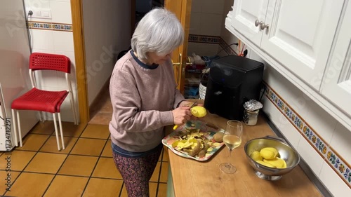 Senior woman peeling potatoes in kitchen preparing ingredients for traditional Spanish omelette