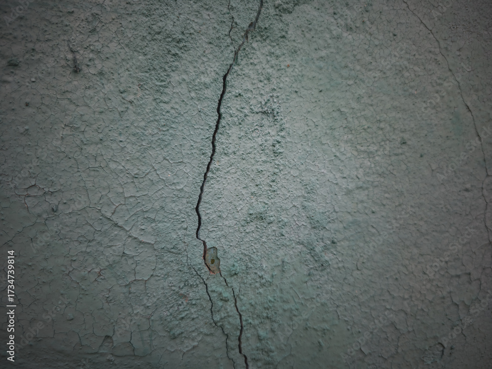 Obraz premium Close-up of a cracked old green wall with peeling paint and rough texture, ideal for backgrounds, design elements, or projects needing vintage rustic surfaces.