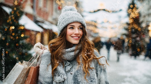 Smiling woman shopping on snowy Christmas street with festive lights