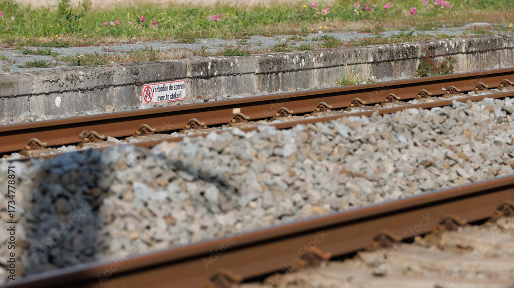 Naklejka premium Cautionary sign near train tracks emphasizes safety importance for travelers