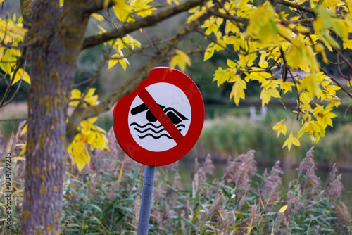фотографія No Swimming sign warns against danger in beautiful autumn lakeside nature settin