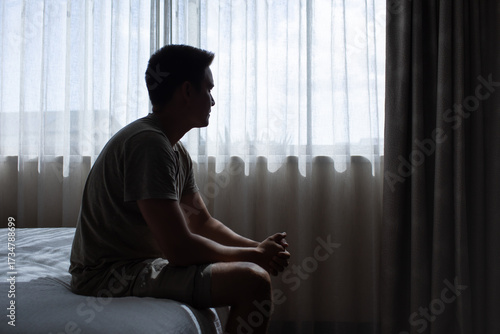 Canvas Print Silhouette of man looking out window thinking sitting on the bed in the bedroom
