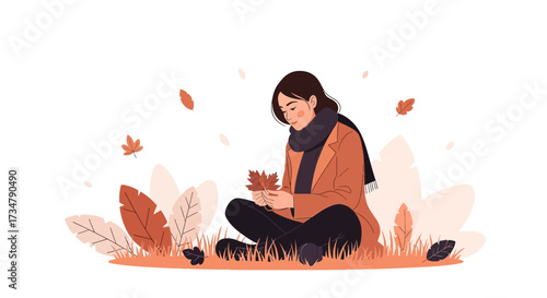 Autumnal scene of a woman sitting in the grass holding a leaf and enjoying the fall