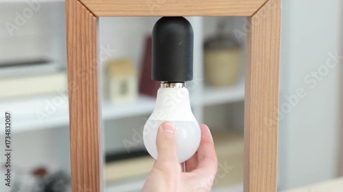 Woman changing light bulb in lamp at home, closeup