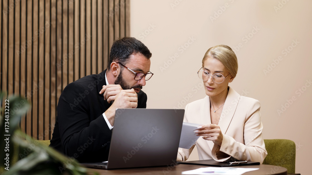 Obraz premium Business professionals engaged in a discussion while reviewing documents in a modern office setting, showcasing collaboration and teamwork in a corporate environment 