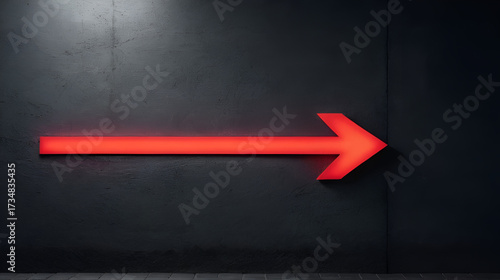 Illuminated red arrow sign pointing left on dark concrete surface