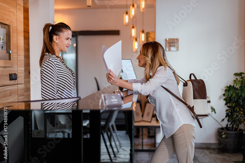 Woman checking in at a hotel reception desk while smiling and interacting with staff member