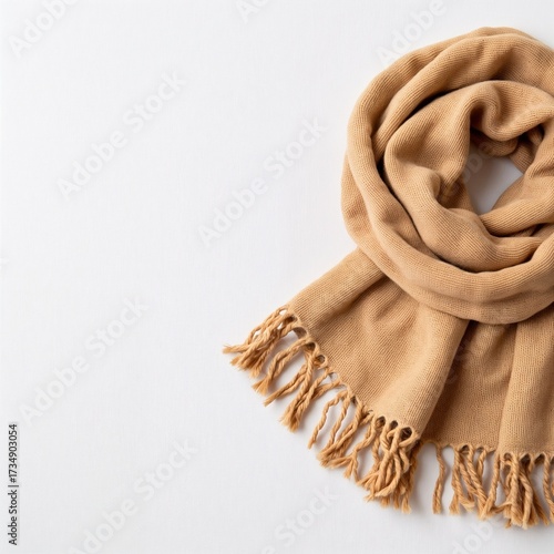 Cozy beige scarf with fringes arranged on a white background  