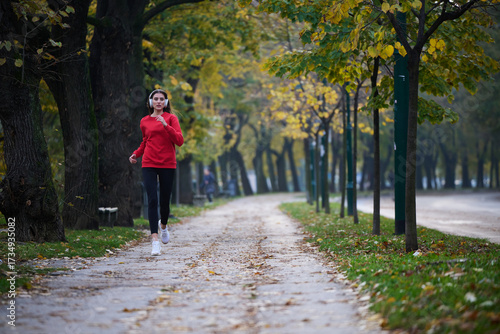 Wallpaper Mural Young beautiful woman running in autumn park and listening to music with headphones on smartphone Torontodigital.ca