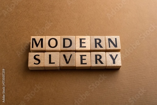 Wooden blocks spelling out 'MODERN SLAVERY' on a textured brown background, highlighting social issues