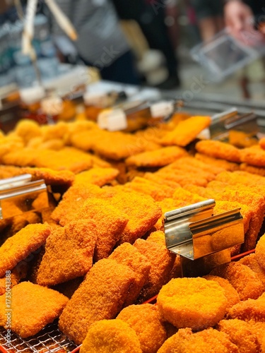 Obraz na plátně A large quantity of breaded and fried food items, possibly chicken nuggets, fish cakes, or katsu, in a food service display