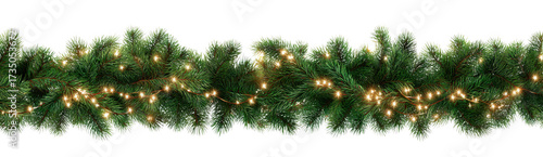 Stylish Christmas garland made of green pine branches adorned with warm white lights, creating festive and cozy atmosphere for holiday celebrations