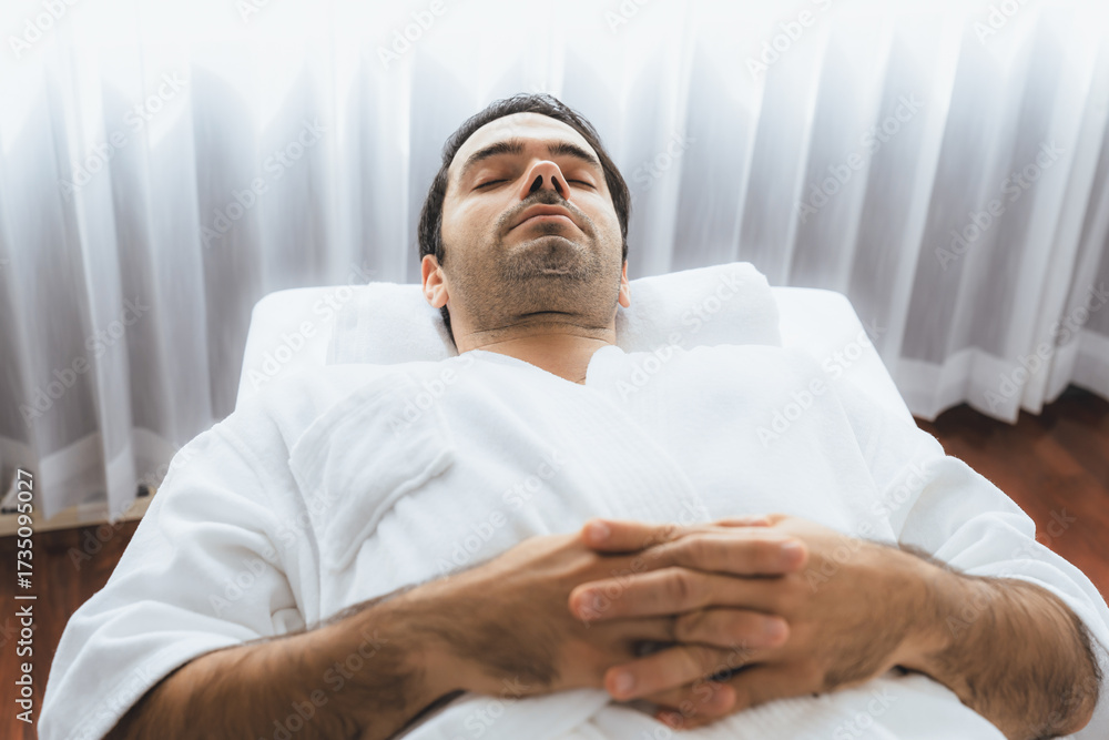Obraz premium Caucasian man customer enjoying relaxing anti-stress spa massage and pampering with beauty skin recreation leisure in day light ambient salon spa at luxury resort or hotel. Quiescent