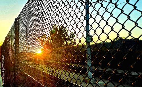 sunrise through a chain link fence