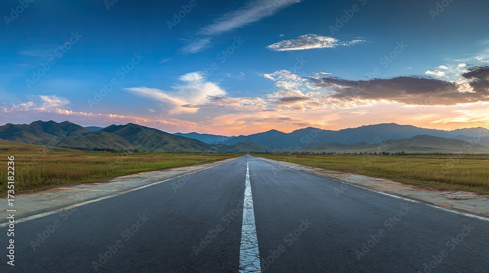 Naklejka premium Asphalt road stretches into a vibrant mountain landscape at sunset