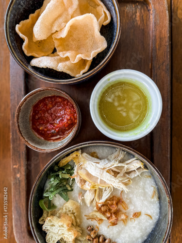 Wallpaper Mural Traditional Indonesian chicken porridge or Bubur Ayam served with crackers, chili sauce, green sauce, and toppings on a wooden tray over rustic wooden table. Torontodigital.ca