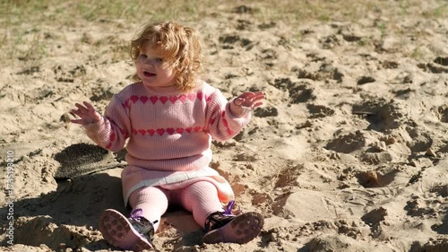 Child playing in sandy area wearing warm sweater on a bright sunny day outdoors