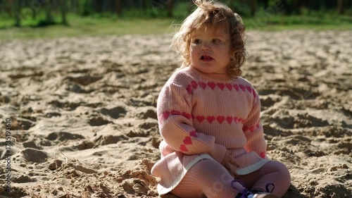 Child playing in sandy area wearing warm sweater on a bright sunny day outdoors