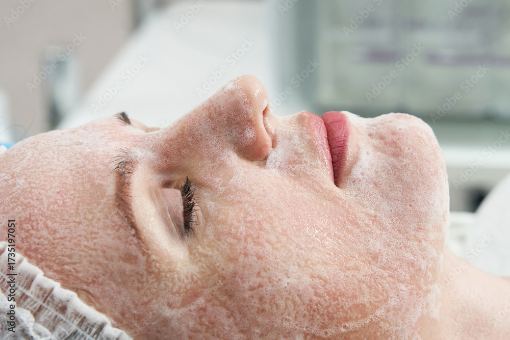Naklejka premium Young pretty woman receiving treatments in beauty salons. Using facial cleansing foam