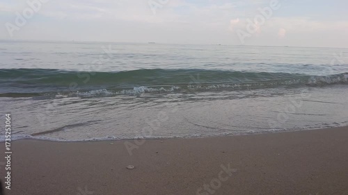 Calm sea waves rolling on sandy beach shore in the morning, relaxing ocean nature footage for travel, vacation, and background use