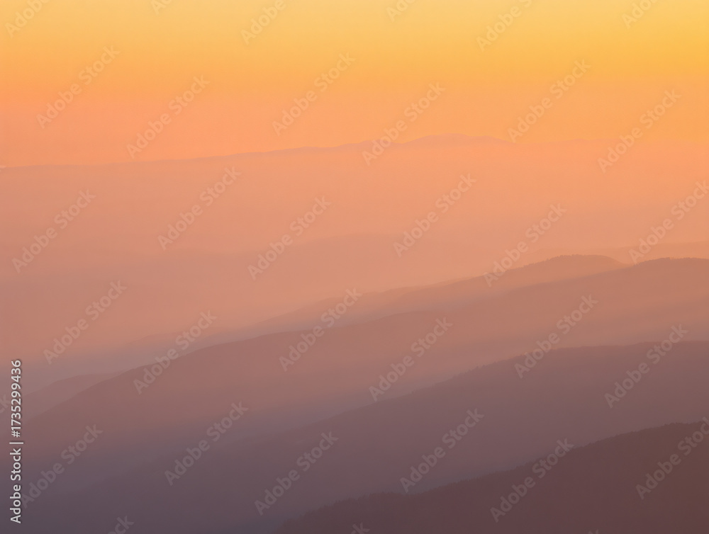 Fototapeta premium A soft gradient sky over hazy mountain ranges with a warm orange and purple color palette at sunrise