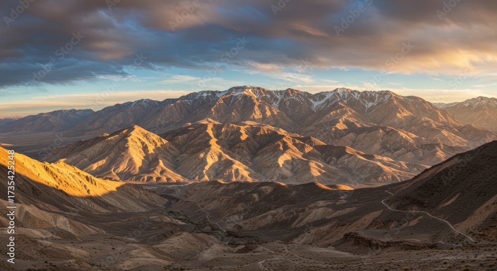 Fototapeta premium Majestic mountain range at sunset with dramatic lighting casting shadows on the textured landscape