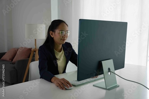 Asian Female Accountant Diligently Working on Desktop Computer. Modern Office Setting for Financial Reporting and Analysis, Highlighting Focus and Professionalism.