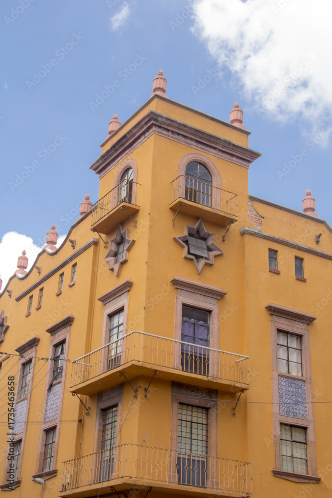 Fototapeta premium Vibrant yellow historic building in Puebla, Mexico, with intricate Talavera tile accents, showcasing colonial and European-Mexican architectural fusion.
