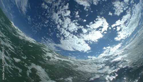 A wide-angle perspective of a powerful ocean wave, showcasing the interplay of water, sky, and clouds.