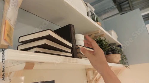 Hand Reaching for Book on Shelf in Home Interior