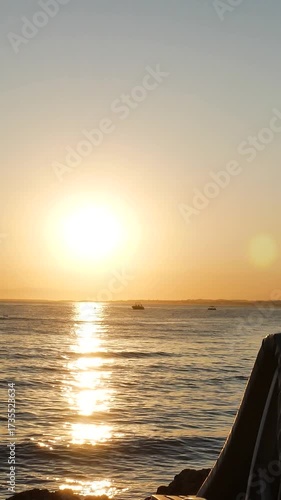 Sunset over the sea on the beach. Empty sun loungers and a folded umbrella from the sun are visible.