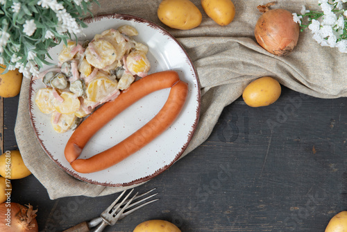 angerichteter Kartoffelsalat mit Wiener in einem kühlen Look auf einem Tisch aus Holz für die winterliche oder weihnachtliche Zeit