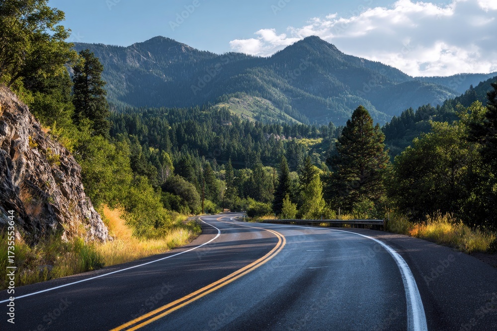 Fototapeta premium Winding road through lush green forest towards majestic mountain peaks