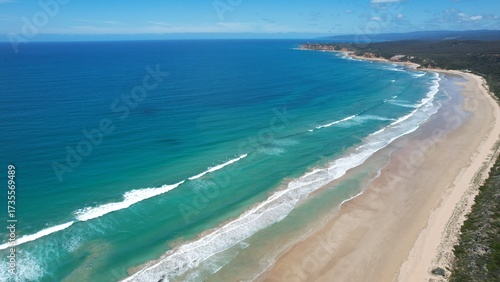 Clean ocean waves breaking on a white sand beach with turquoise emerald colored water