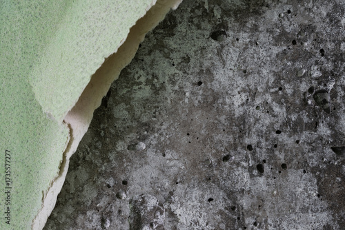Torn old faded paper wallpaper with a retro pattern. Tattered scraps of paper on a concrete wall. Vintage texture for background and design. Closeup view with copy space. High resolution.