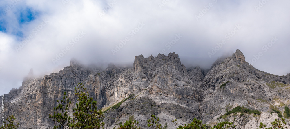 Fototapeta premium Alpine mountain peaks emerging above a drifting cloud layer