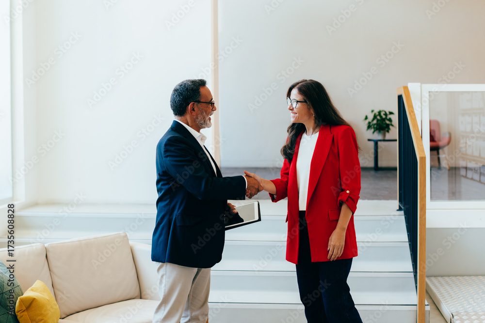 Fototapeta premium Senior management team members shaking hands professionally near a staircase