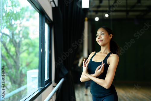 Free Download Graceful young ballerina practicing arm position near the barre in a dance studio - GFXLoad