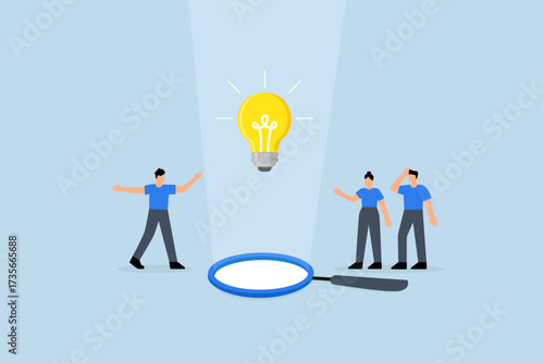 team of business professionals observing a lightbulb suspended from magnifying glass
