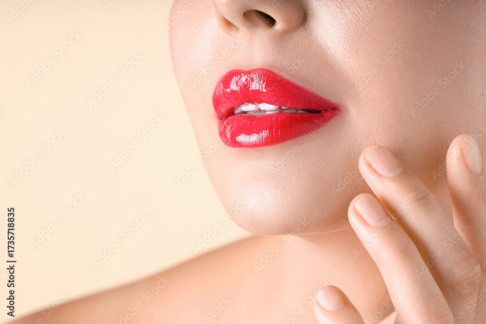 Obraz premium Woman with beautiful red lipstick on her lips against beige background, macro view. Space for text