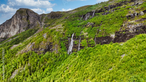 Obraz na płótnie A mountain with a lush green hillside and a waterfall