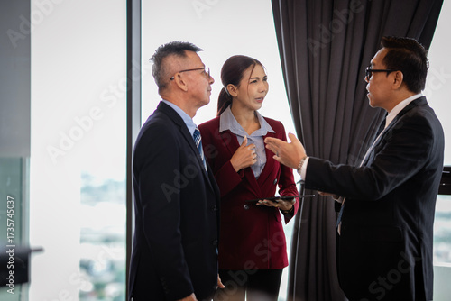 Foto Group of Asian executives in formal suits discussing opportunities, reflecting teamwork, management, and leadership values that strengthen workplace culture and relationships